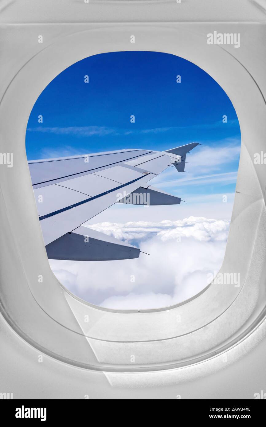 Vista attraverso la finestra dell'aeroplano, ala sopra le nuvole Foto Stock