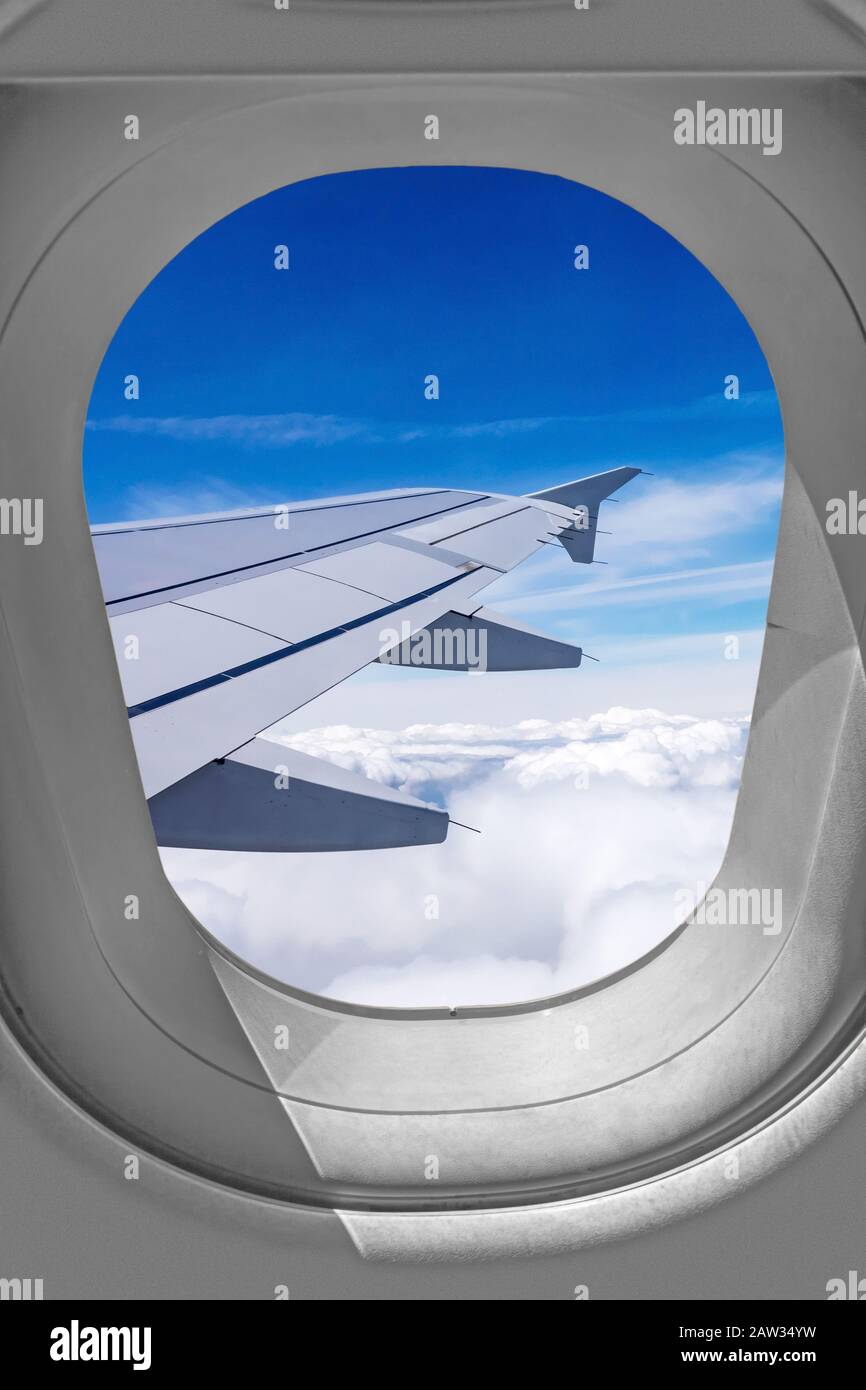 Vista attraverso la finestra dell'aeroplano, ala sopra le nuvole Foto Stock