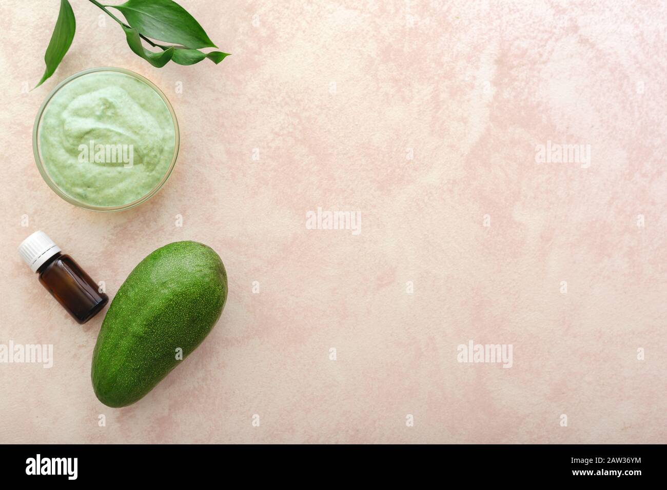 Maschera viso avocado in vaso di vetro con foglie e avocado, olio. Maschera nutriente fatta in casa di avocado purè. Ricetta fai da te per cosmetici Fatti In Casa, pelle Foto Stock
