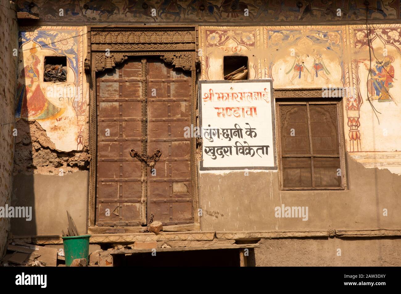 India, Rajasthan, Shekhawati, Mandawa, Akram Ka Haveli, resti di antiche mura dipinte storiche intorno alla vecchia porta della casa di legno Foto Stock