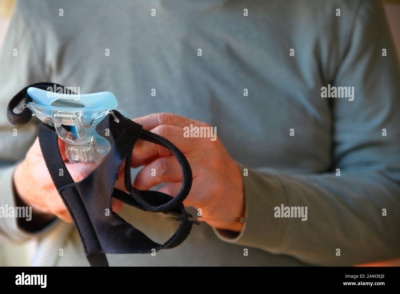 Un uomo che sostiene il suo apnea nel sonno maschera facciale e copricapo Foto Stock