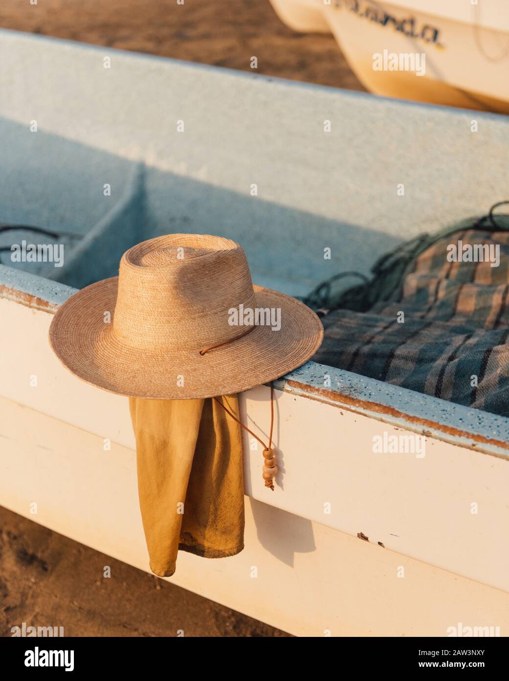 Un cappello del viaggiatore riposa lungo un lato di una barca da pesca Foto Stock