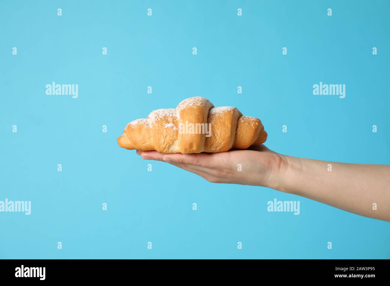 Cornetto femmina in mano su sfondo blu, spazio per testo Foto Stock
