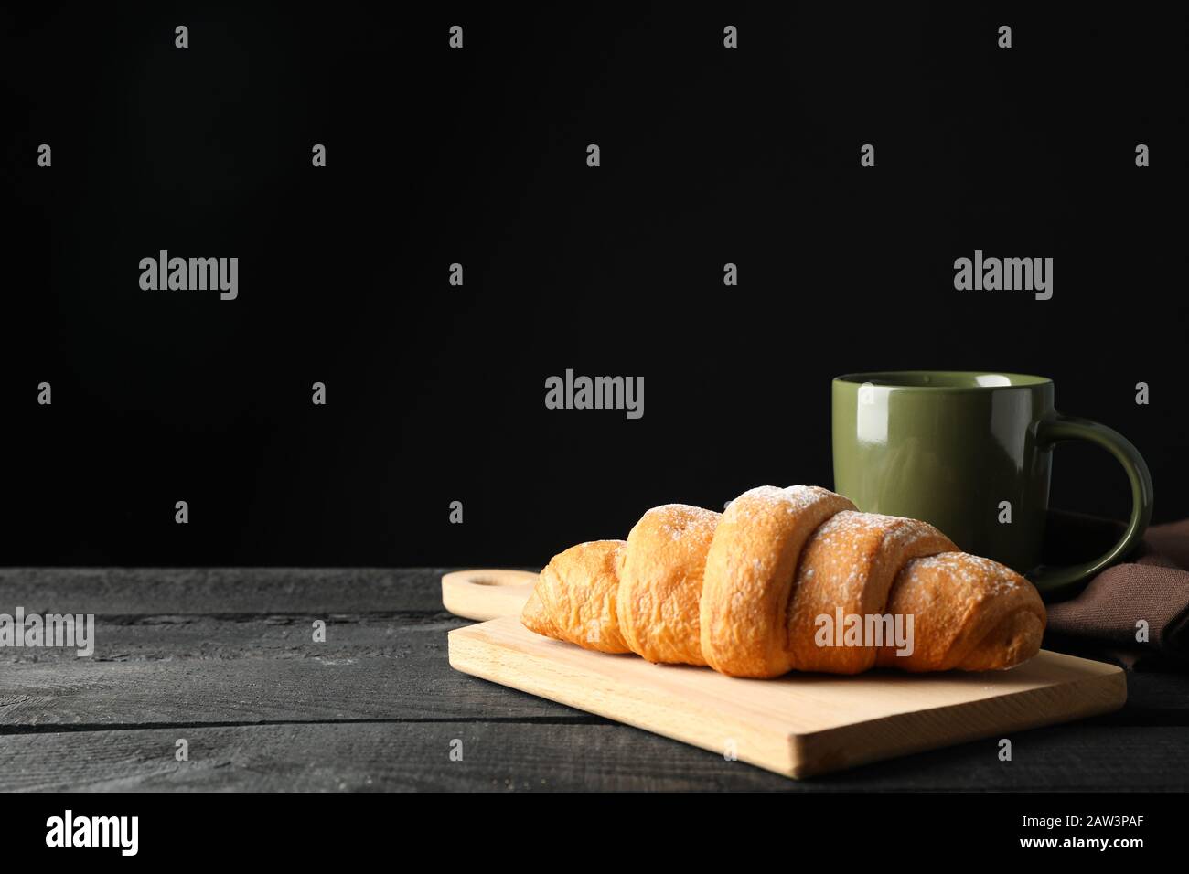 Tavola con croissant e tazza su fondo di legno, spazio per il testo Foto Stock