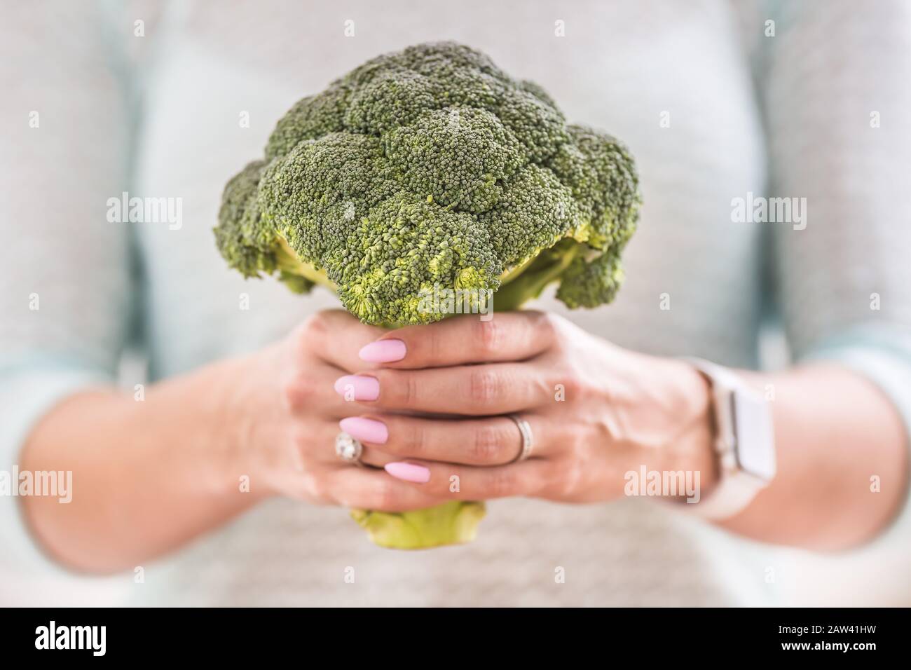 Le mani di una giovane donna tengono un broccoli fresco. Foto Stock