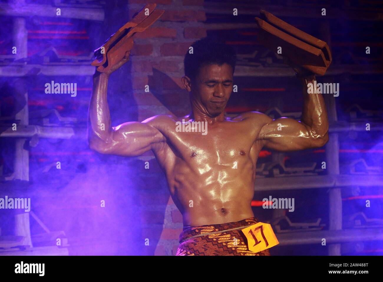 Un atleta di bodybuilding sta mostrando i suoi muscoli del corpo alzando un certo numero di mattonelle in una competizione bodybuilding tra il 2019 Jatiwanggi Cup concorso alla Genteng Two Brothers Factory, Jatiwangi, Majalengka, West Java, Domenica 11 agosto 2019. La competizione di bodybuilding fra le aziende di industria delle mattonelle è stata iniziata come apprezzamento per la fabbrica dei due fratelli di Genteng, Jatiwangi, Majalengka, Java occidentale, domenica 11 agosto 2019. Operai di industria delle mattonelle. Oltre ad essere stato tenuto per dare il benvenuto alla 74th Giornata dell'Indipendenza Indonesiana. Foto Stock