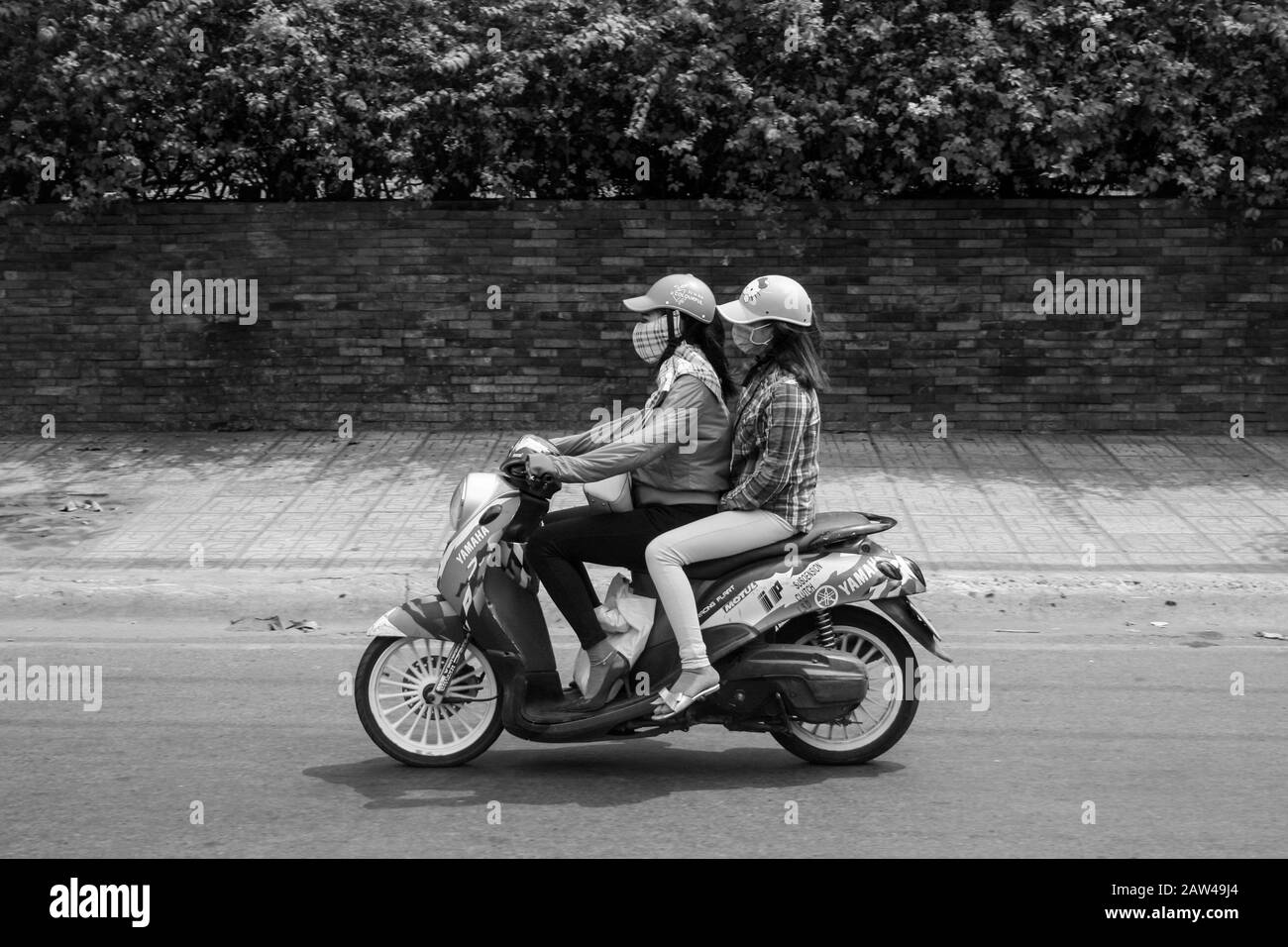 Due Signore indossano maschere facciali su un ciclomotore nella città di ho Chi Minh, in Vietnam Foto Stock