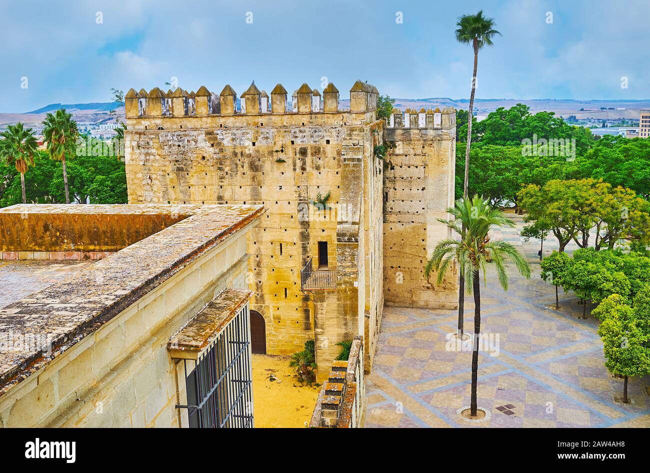 Goditi la vista dall'alto sulla torre Medievale Degli Omaggi e la lussureggiante vegetazione di Piazza Monti, da Alcazar, Jerez, Spagna Foto Stock