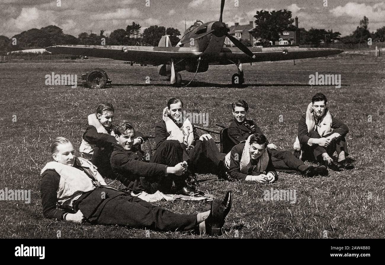 Piloti di 32 Squadron a Biggin Hill, Kent, Inghilterra nel luglio 1940, rilassandosi poco prima delle riprese di apertura della Battaglia di Gran Bretagna. Dietro di loro un Hawker Hurricane aereo da combattimento a posto singolo. Più tardi fu oscurato nella coscienza pubblica dal ruolo del Supermarine Spitfire durante la battaglia di Gran Bretagna nel 1940, ma l'uragano inflisse circa il 70% delle perdite sostenute dalla Luftwaffe nell'impegno, e combatté in tutti i maggiori teatri della Seconda guerra mondiale. Foto Stock