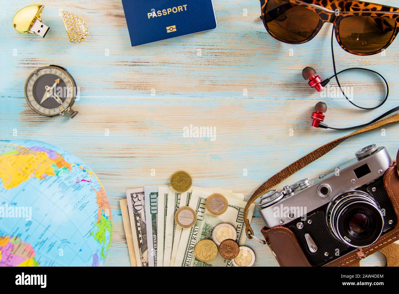 Tour planante immagine concettuale su sfondo blu di legno vecchia fotocamera, dolari, carta mammaria, passaporto e mappa occhiali cuffie con copyspace Foto Stock