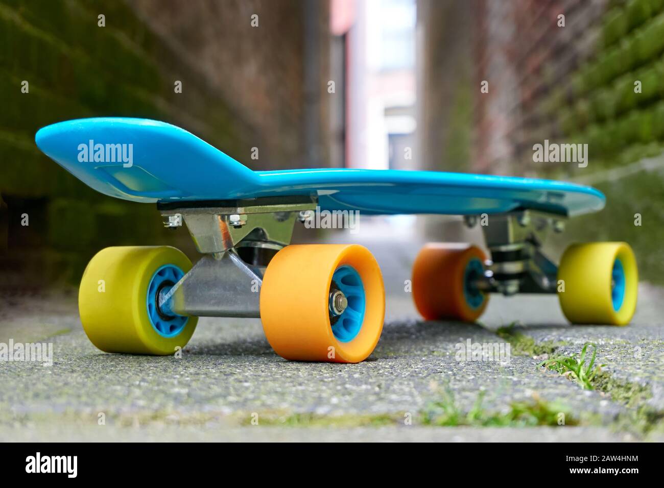 Mini bordo in plastica blu o skate board con ruote gialle e arancioni in un  vicolo con luce alla fine Foto stock - Alamy
