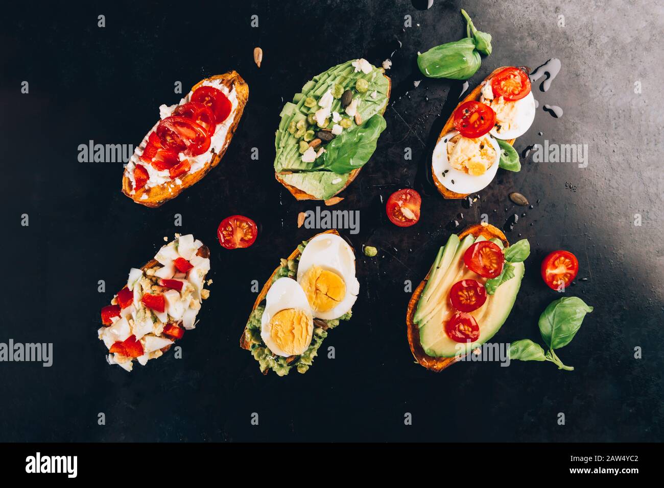 Toast di patate dolci con avocado, uova sode, pomodori e semi di sesamo su sfondo scuro. Concetto di pasto sano. Cibo pulito, cibo Pescario, vista dall'alto Foto Stock