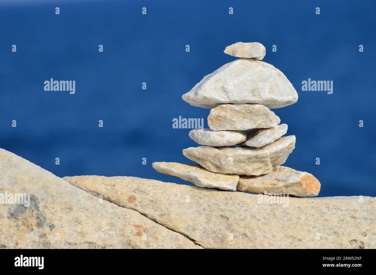 Pila di pietre di marmo zen su una scogliera di marmo contro sfondo blu bokeh, Grecia, orientamento orizzontale Foto Stock