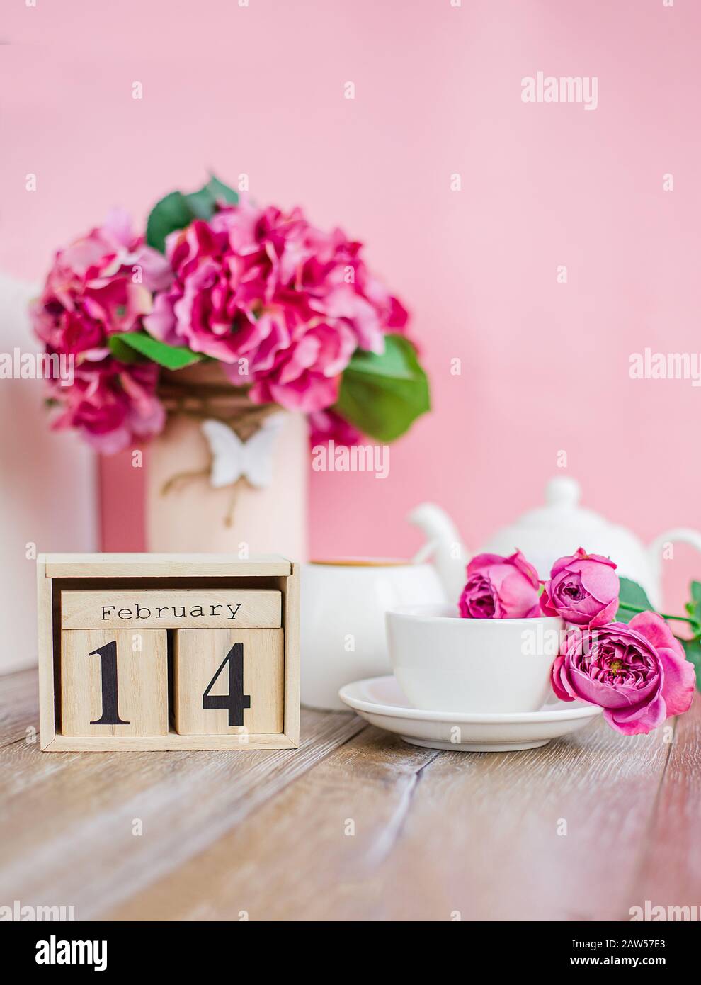 Buon San Valentino. Calendario in legno per il 14 febbraio con fiori una tazza bianca. Foto Stock