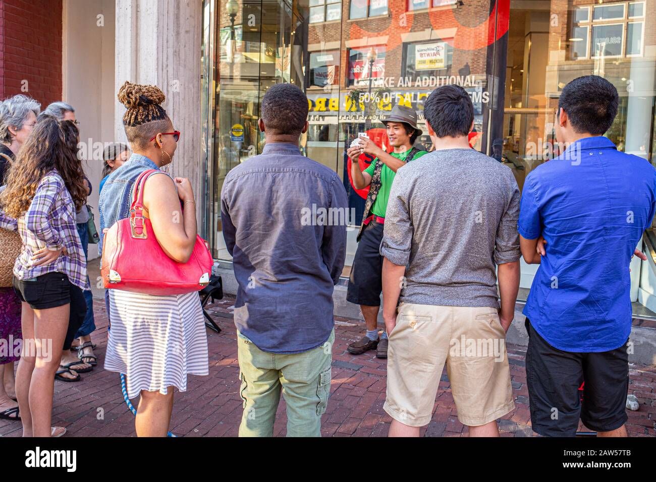Una piccola folla che guarda un artista di strada intrattenere Foto Stock