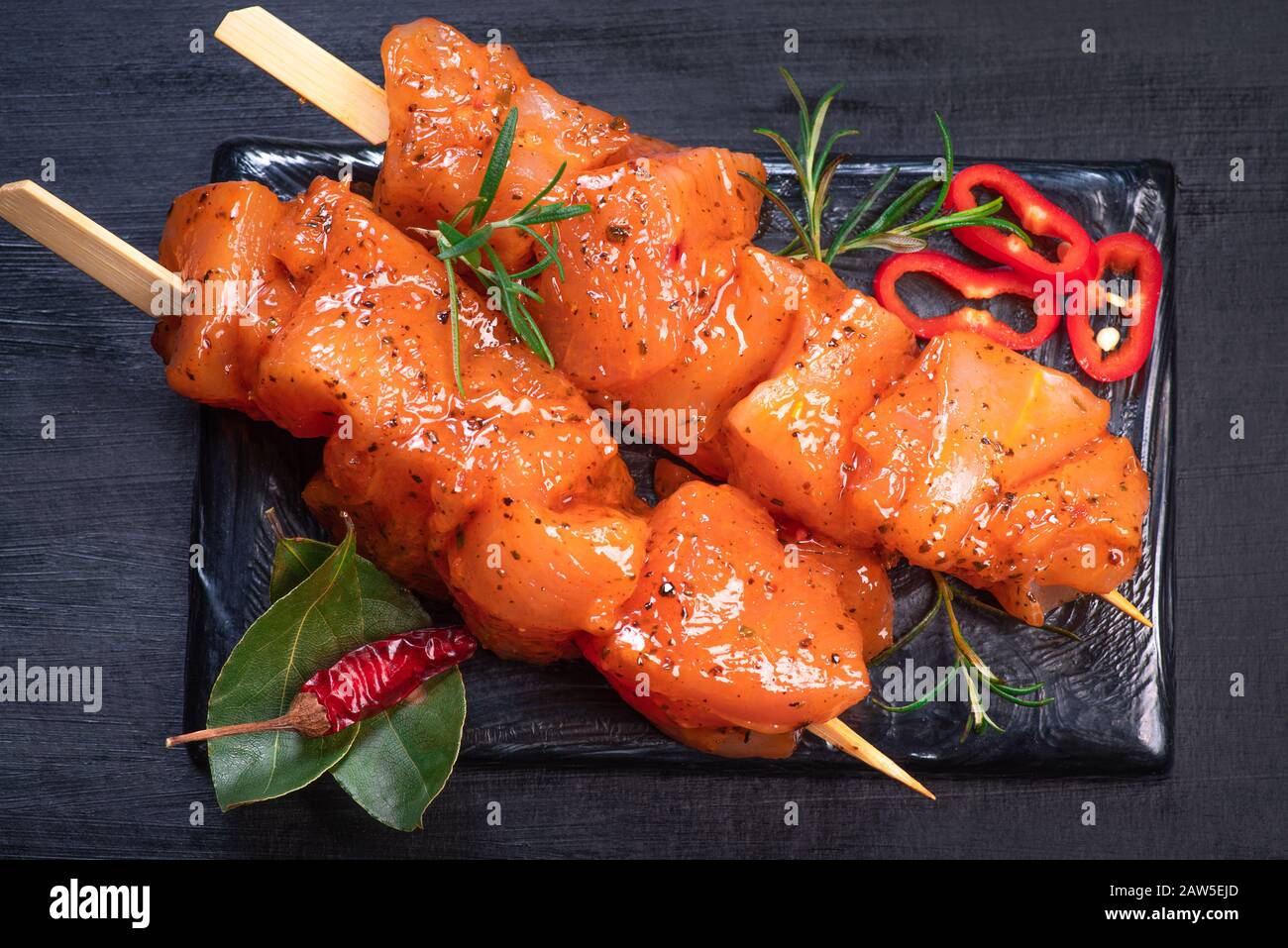 Spiedini Di Pollo Crudi In Marinata Con Spezie Su Un Piatto Nero E Su Un Tavolo