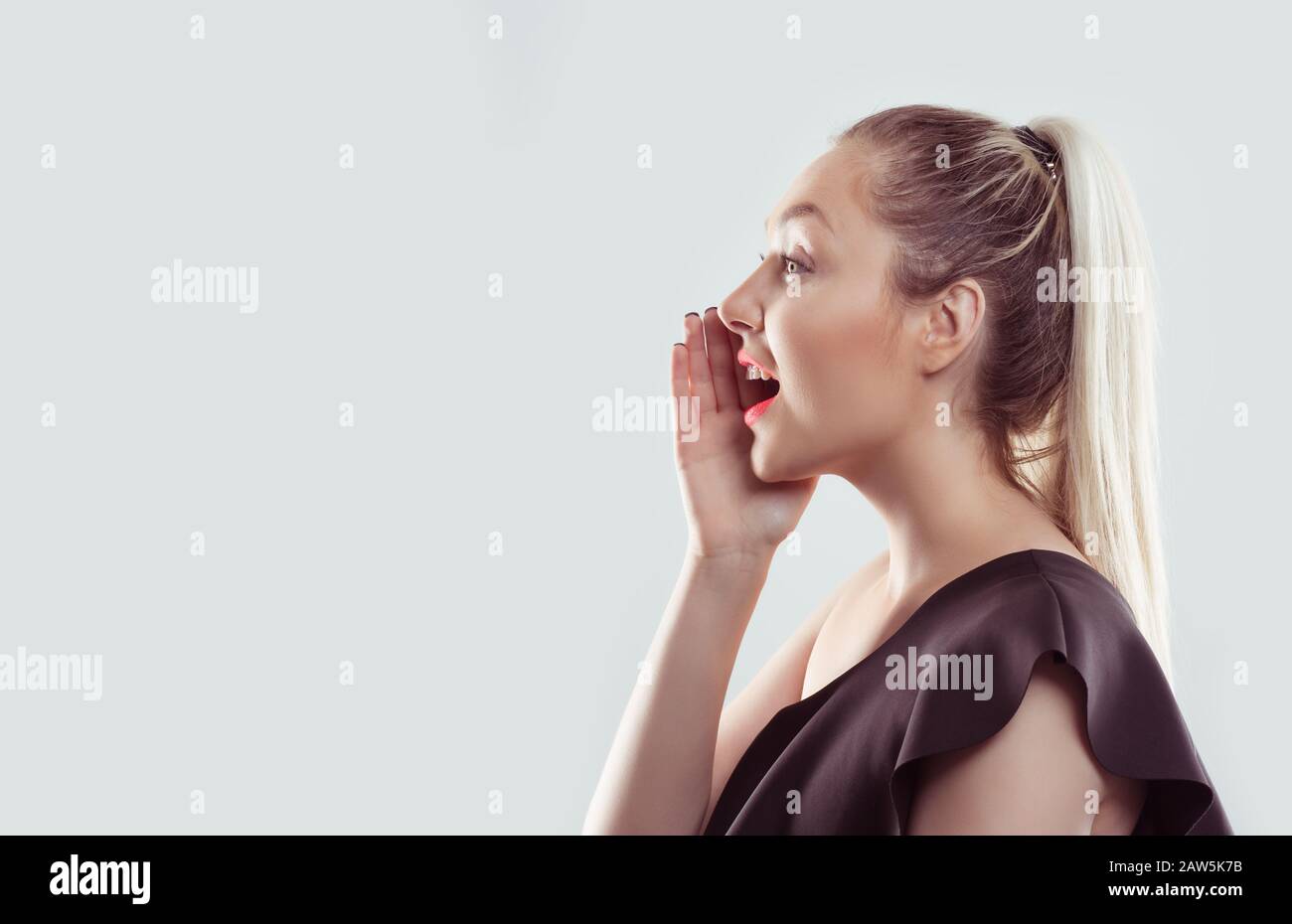 Ho un segreto per dirvi. Closeup ritratto di una donna in profilo sussurrando un pettegolezzo isolato bianco grigio chiaro sfondo Foto Stock