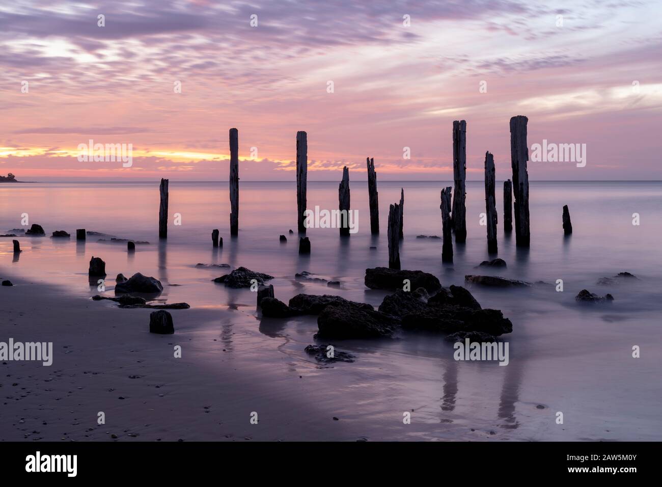 Port Willunga Beach jetty rovine in Australia del sud alight con gli inusuali colori pastello e porpora del tramonto. Foto Stock