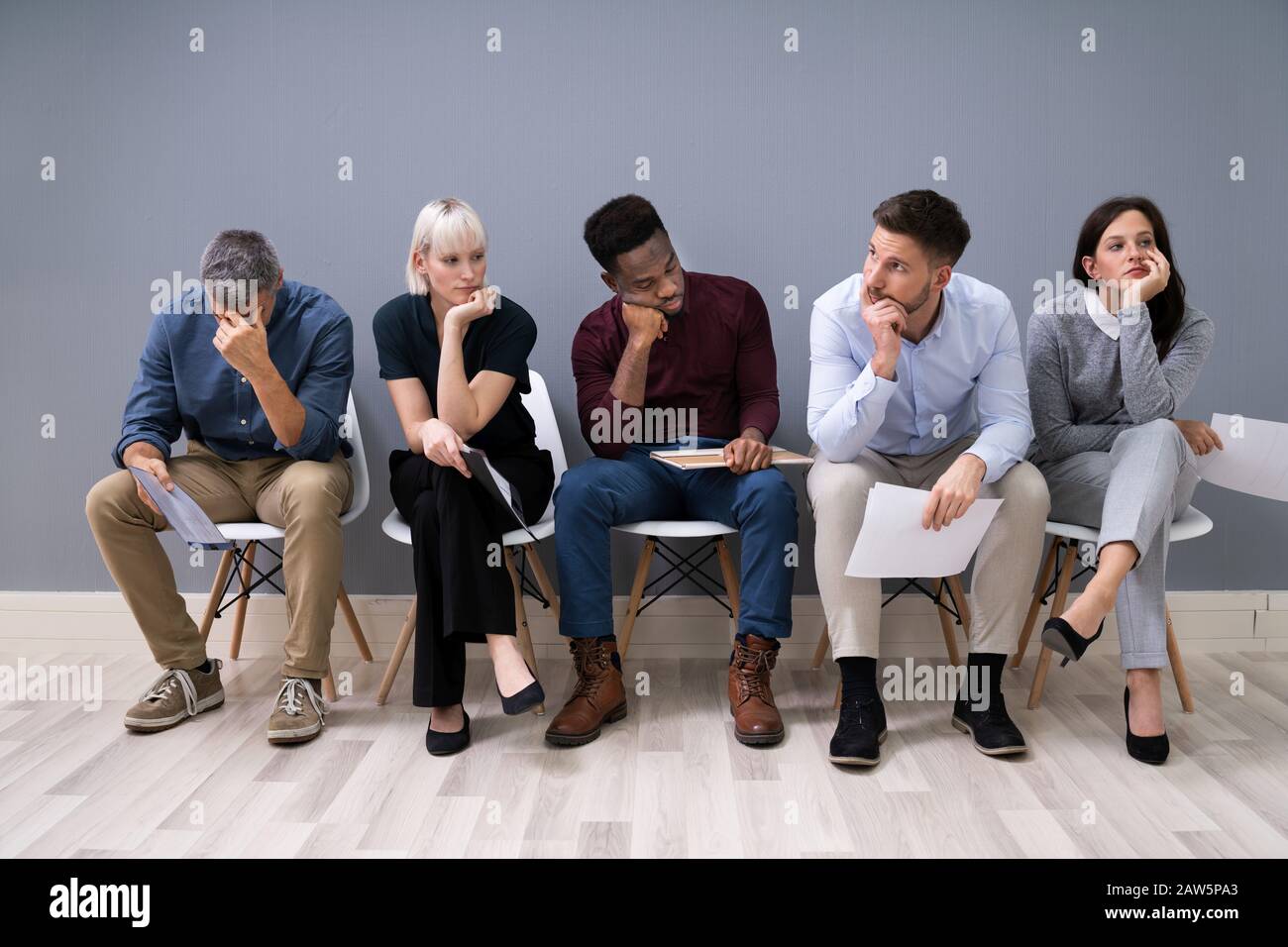 La gente di affari sono annoiarsi mentre è seduto su una sedia in attesa per il colloquio di lavoro in ufficio Foto Stock