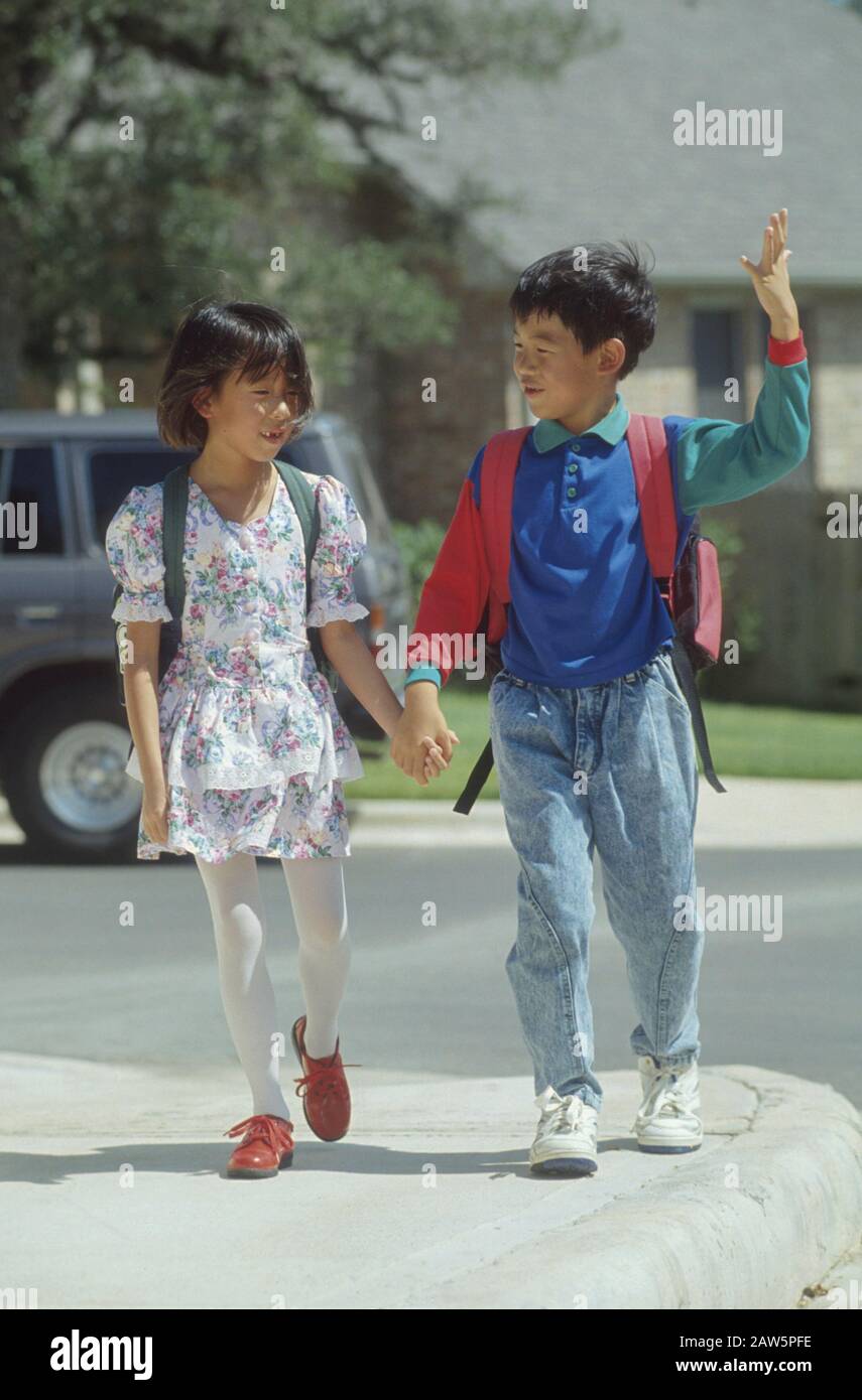 Fratello asiatico-americano e sorella che camminano a casa dalla scuola insieme ad Austin, Texas. Foto Stock