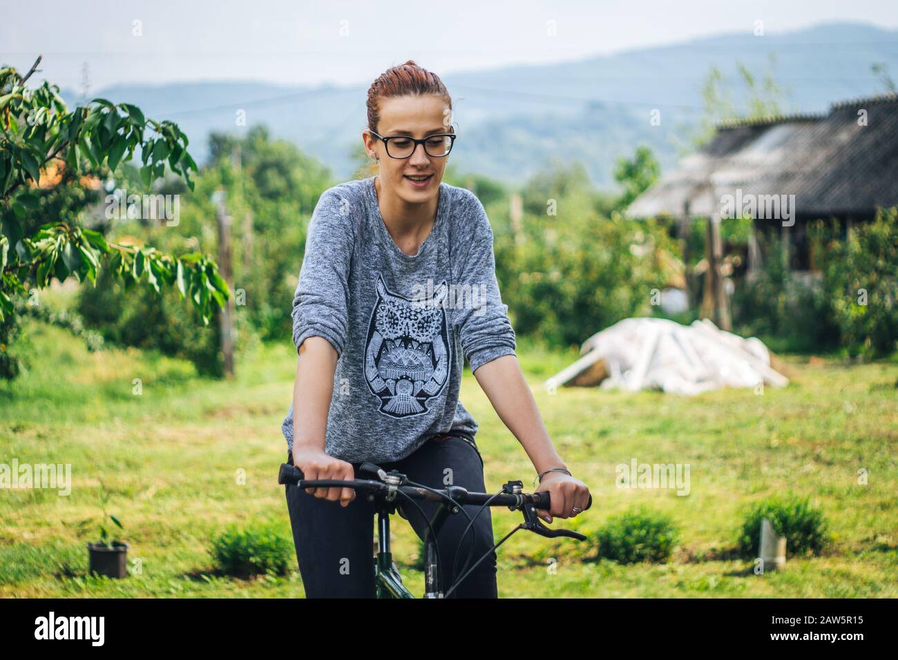 Donna che guida una bicicletta in una fattoria Foto Stock
