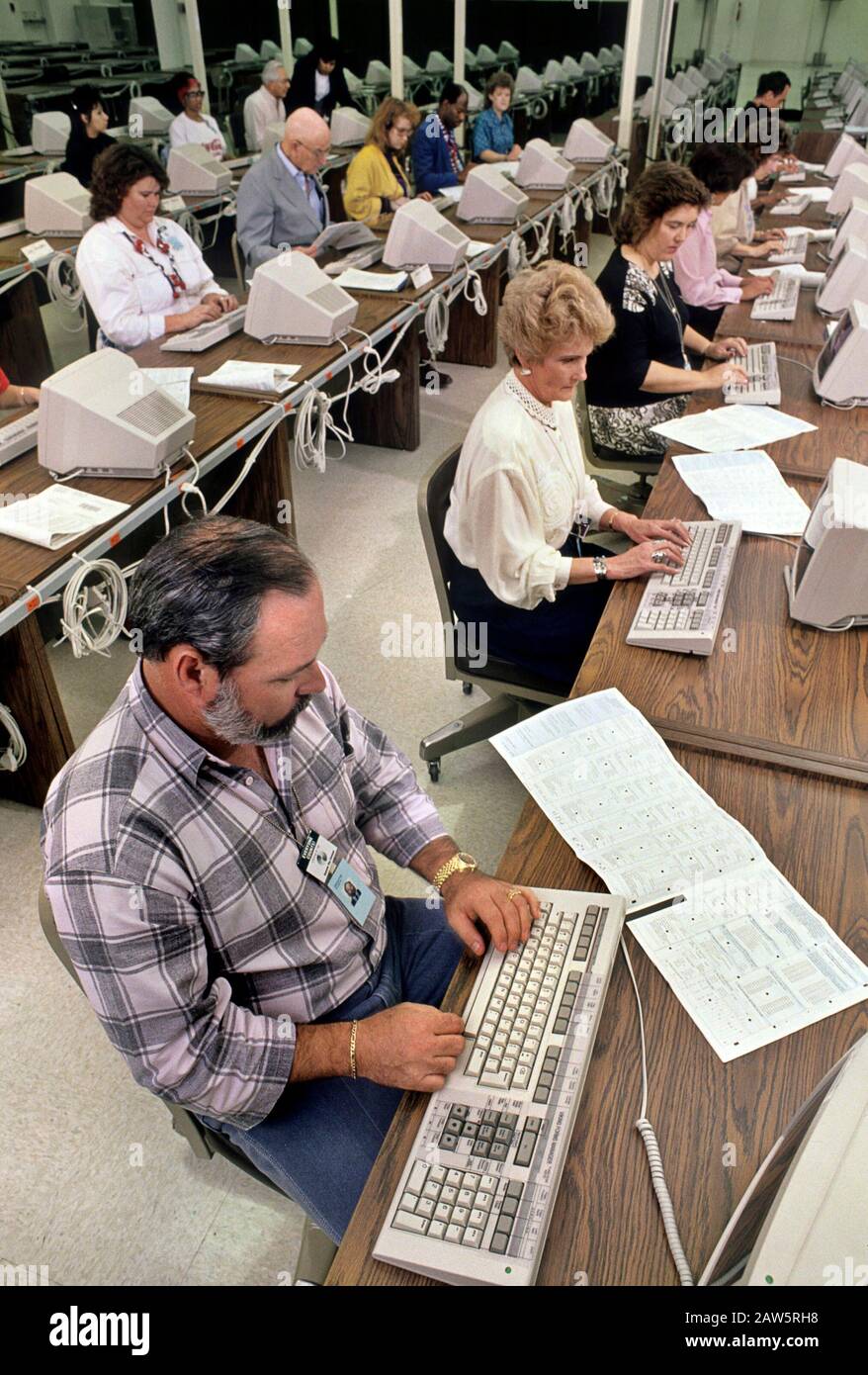 Austin Texas USA, 1990: Dozzine di impiegati per l'immissione di dati per lo più femminili lavorano in una grande stanza in una struttura di elaborazione di censimento degli Stati Uniti mentre milioni di Americani ritornano le forme di censimento per il conteggio decennale delle persone che vivono nel paese. ©Bob Daemmrich Foto Stock