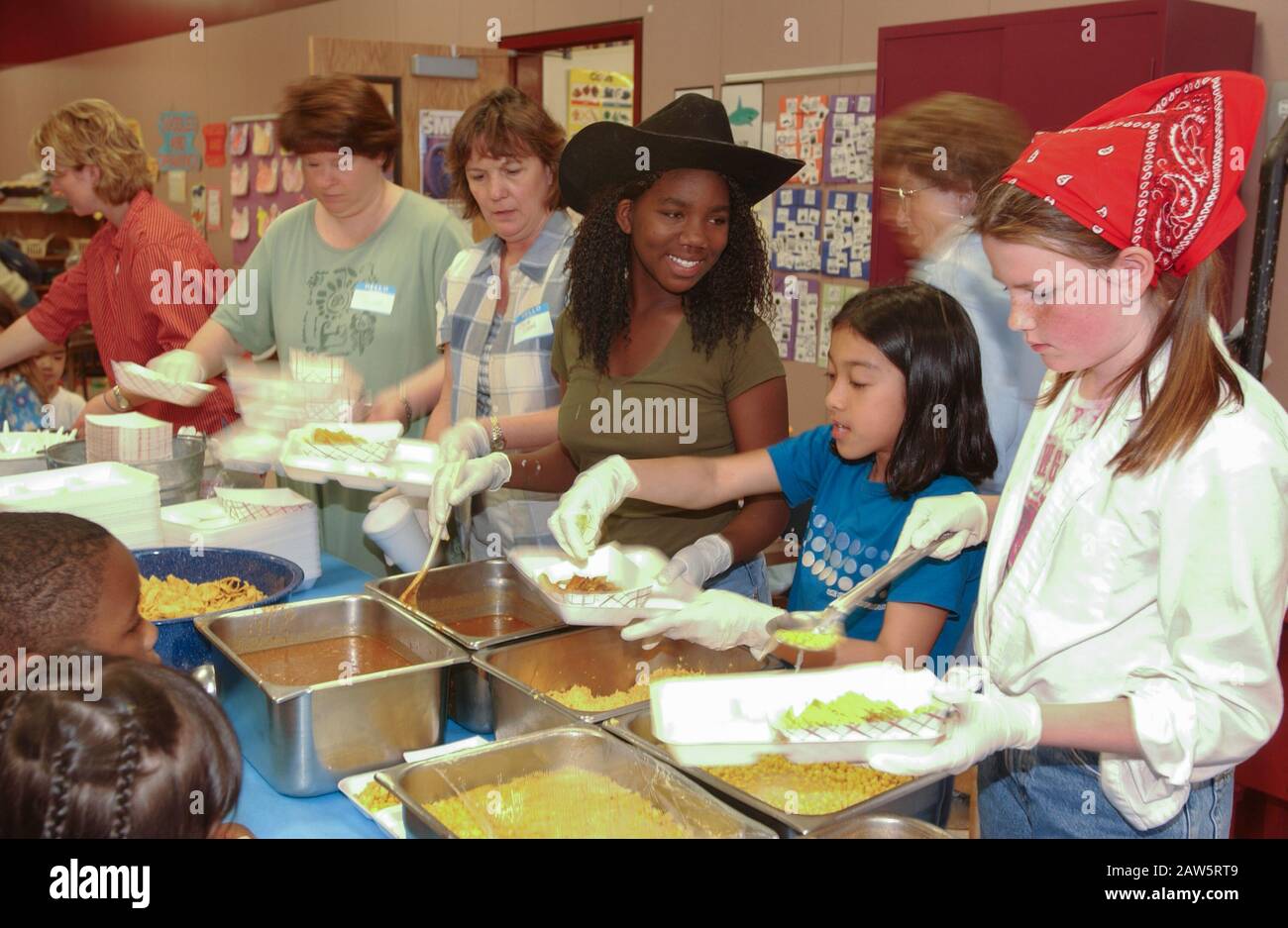 Gli studenti del quinto grado servono il pranzo alla classe dell'asilo durante il 'Kindergarten Rodeo' dove i bambini mangiano cibo in stile ranch e giocano a giochi all'aperto a tema ranch come esperienza di apprendimento presso una scuola elementare di Austin. Foto Stock