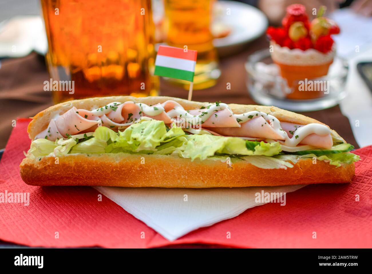 Un pranzo colorato e ben presentato di un panino club e birre in una caffetteria sul marciapiede, completa di una bandiera ungherese a Budapest, Ungheria. Foto Stock