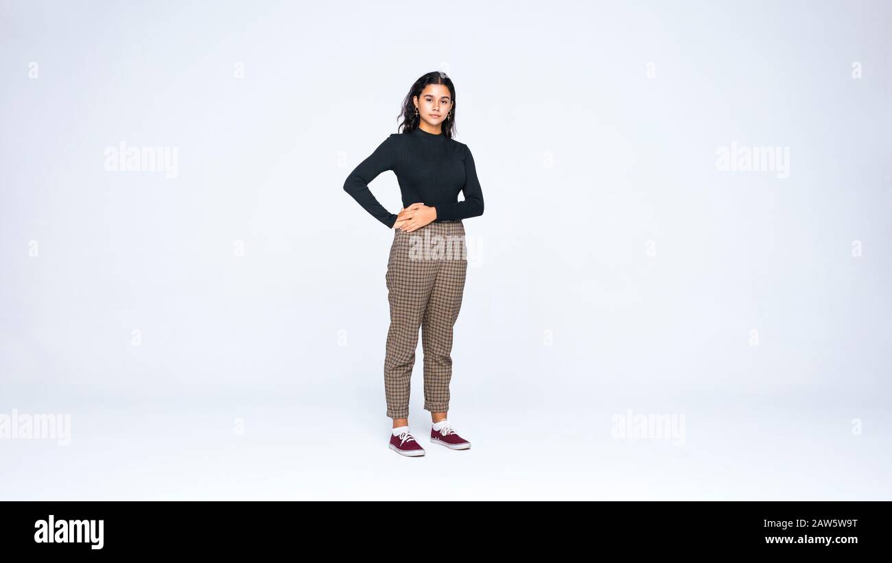 Giovane donna che guarda la macchina fotografica. Donna in piedi isolato su uno sfondo bianco. Foto Stock