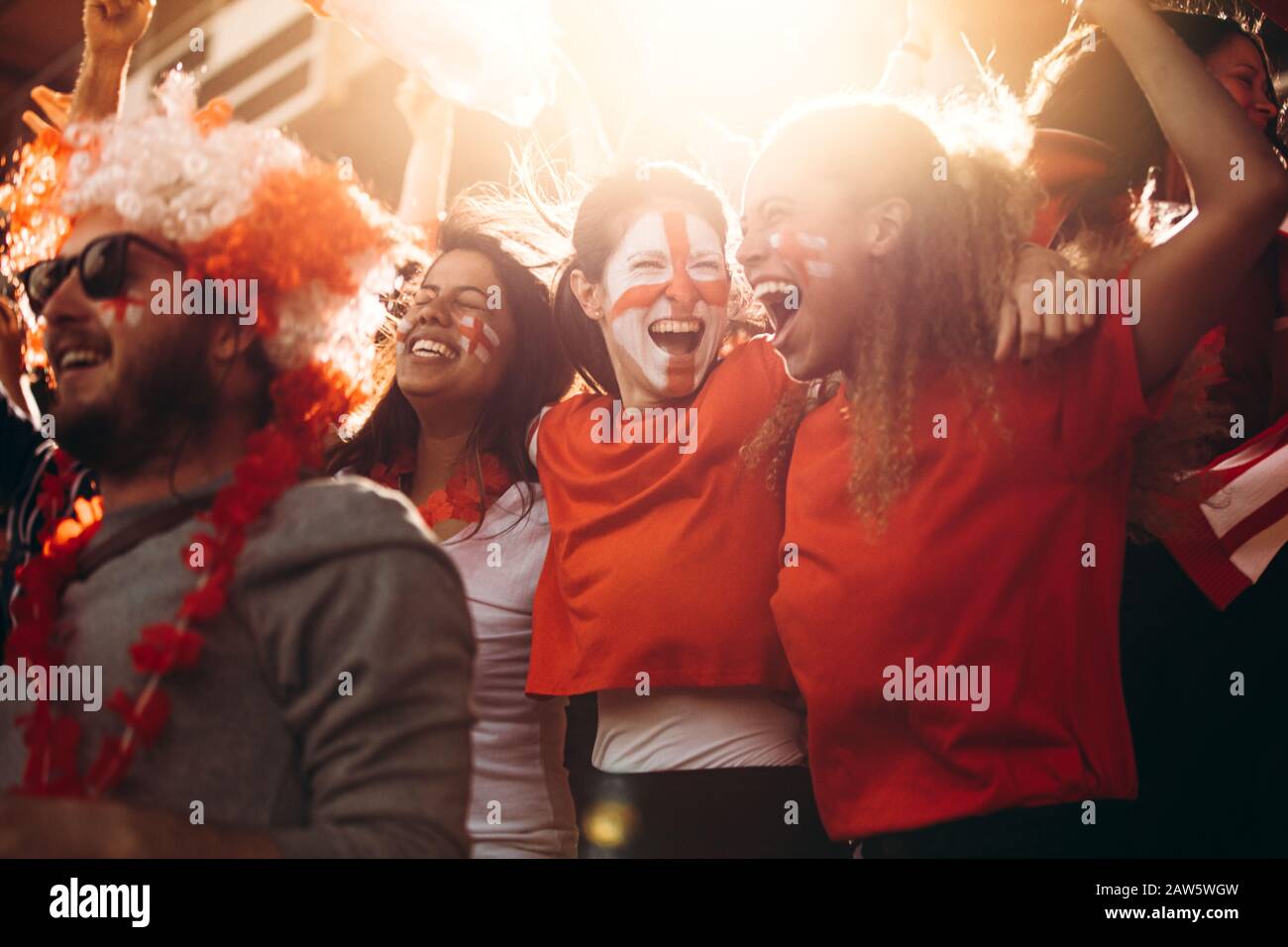 Inghilterra tifosi di calcio rallegrando in stand. Le donne con bandiera inglese dipinte sul loro volto divertendosi nella zona dei tifosi allo stadio. Foto Stock