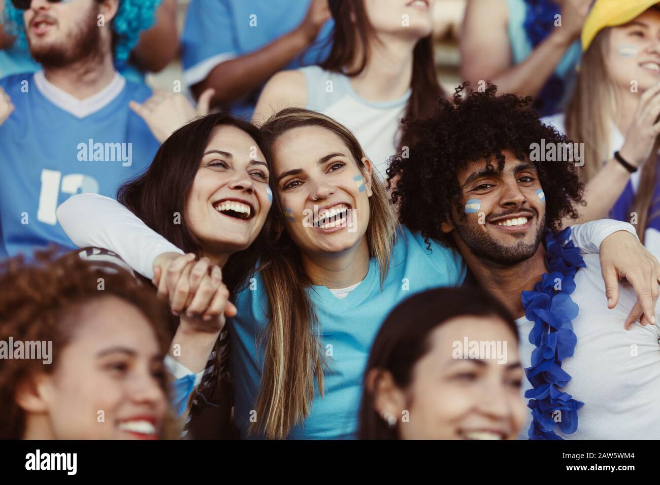 Gruppo di tifosi che guardano partite di calcio nello stadio. Gruppo di appassionati di calcio argentini che guardano con entusiasmo allo stadio e che si divertano a guardare una partita. Foto Stock