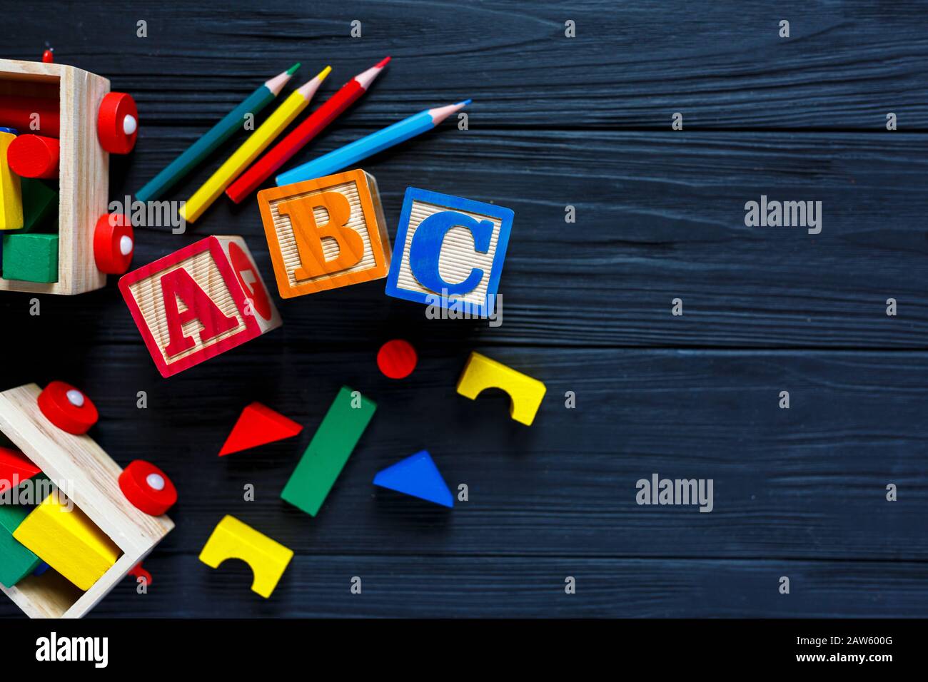 Blocchi di legno con lettere B C, treno, giocattoli per lo sviluppo della creatività su sfondo nero. Giochi educativi per asilo, bambini prescolare. Foto Stock