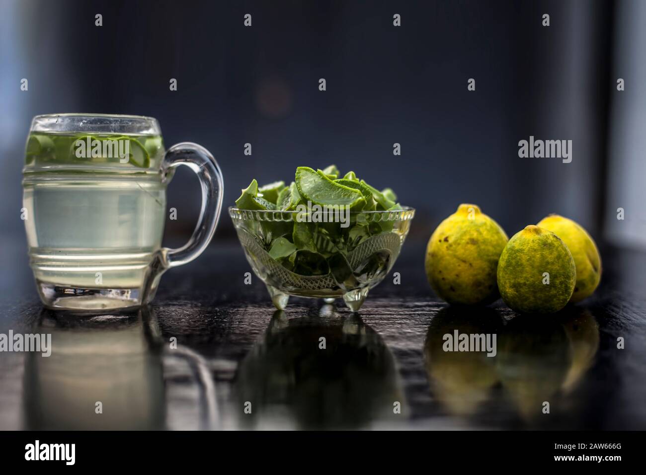 In prossimità della tazza di vetro su una superficie di legno contenenti aloe vera e il succo di limone detox bere insieme con il suo intero ingredienti grezzi con esso. Sho orizzontale Foto Stock