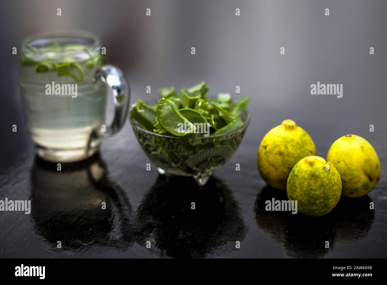 In prossimità della tazza di vetro su una superficie di legno contenenti aloe vera e il succo di limone detox bere insieme con il suo intero ingredienti grezzi con esso. Sho orizzontale Foto Stock