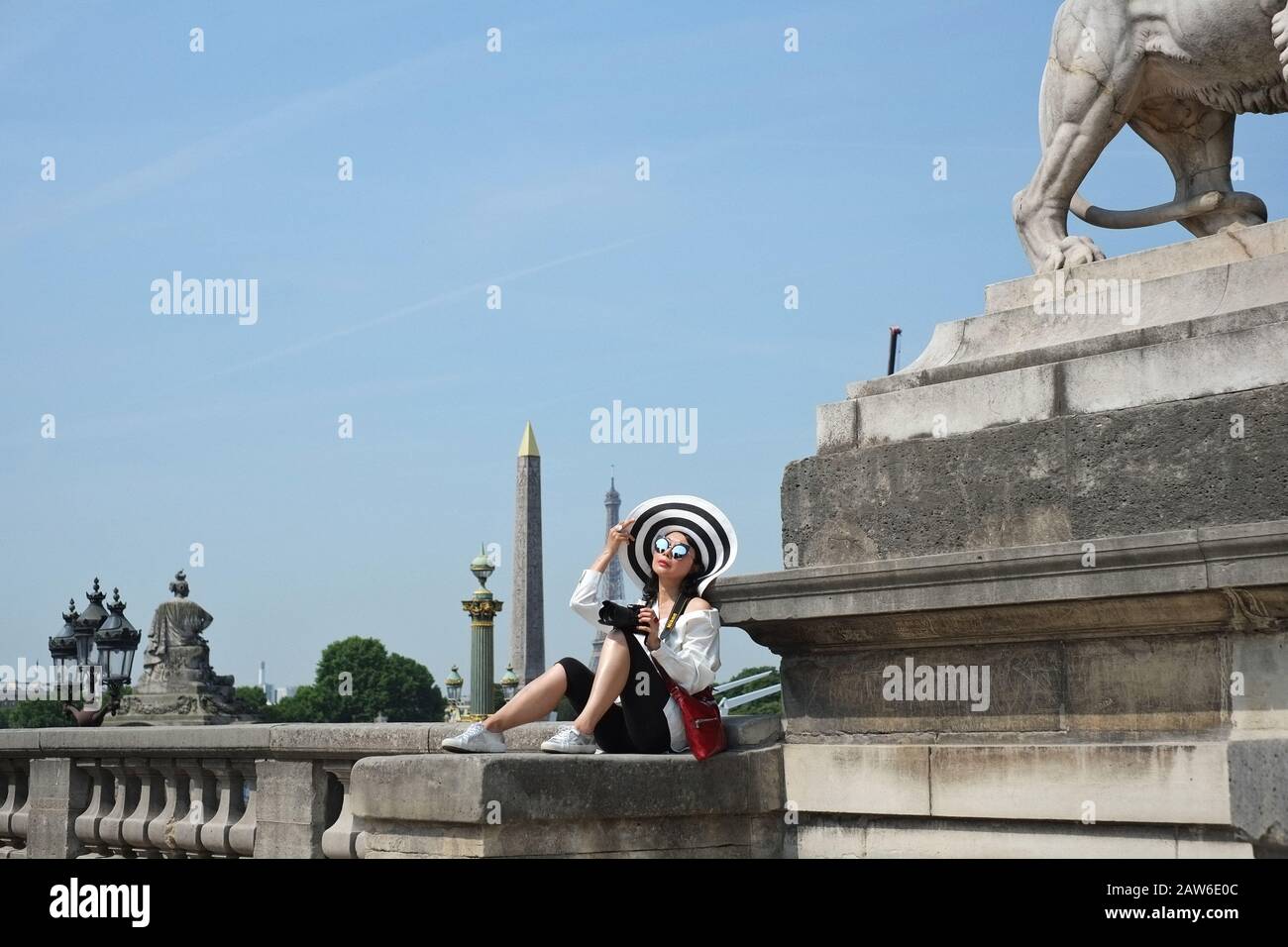 Una giovane donna chic su una balaustra all'angolo del Giardino delle Tuileries, con una statua del leone, lampade, obelisco di Luxor, Torre Eiffel e Place de la Concorde Foto Stock