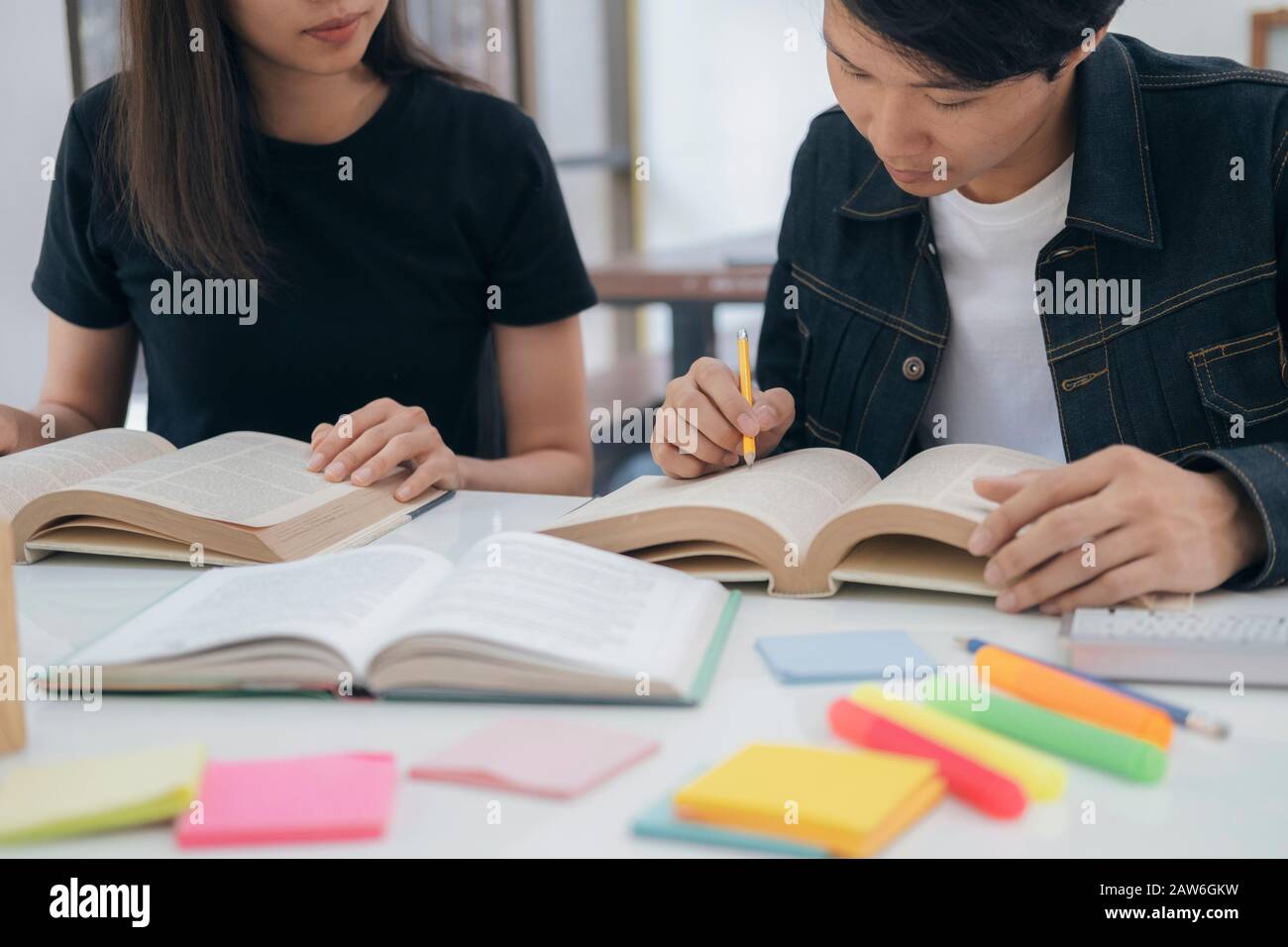 Apprendimento, istruzione e concetto scolastico. Giovane donna e uomo che studiano per una prova o un esame. Tutor libri con amici. Il campus dei giovani studenti aiuta la frie Foto Stock