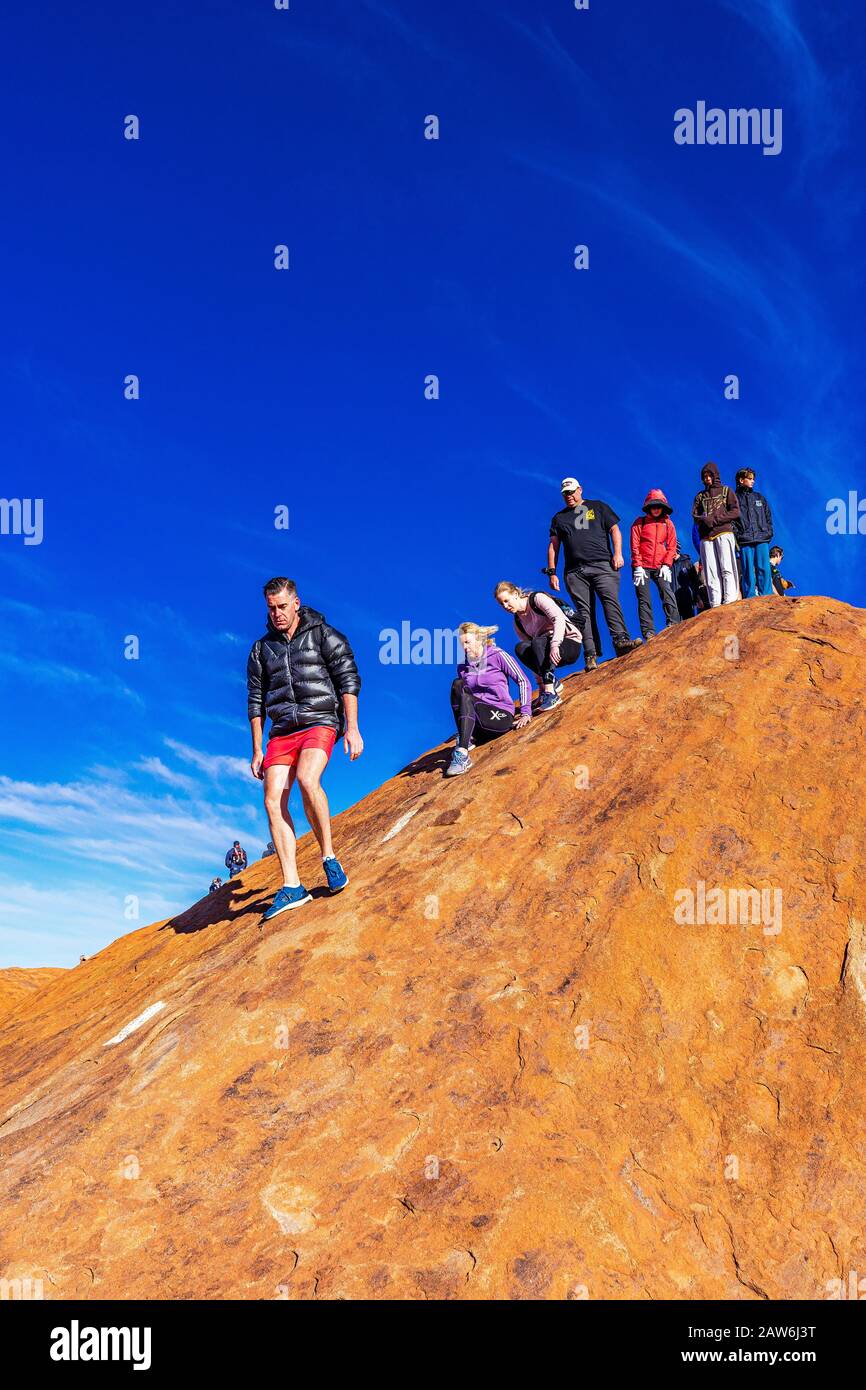 I turisti si arrampicano sul ripido terreno ondulato sulla cima di Uluru. Northern Territory, Australia Foto Stock