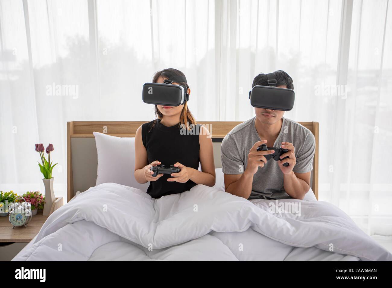 Coppia asiatica amante Godendo giocando Videogame in camera da letto, coppia Asia amante sensazione di divertimento felice e realtà virtuale, VR giocare insieme i giochi mentre l Foto Stock