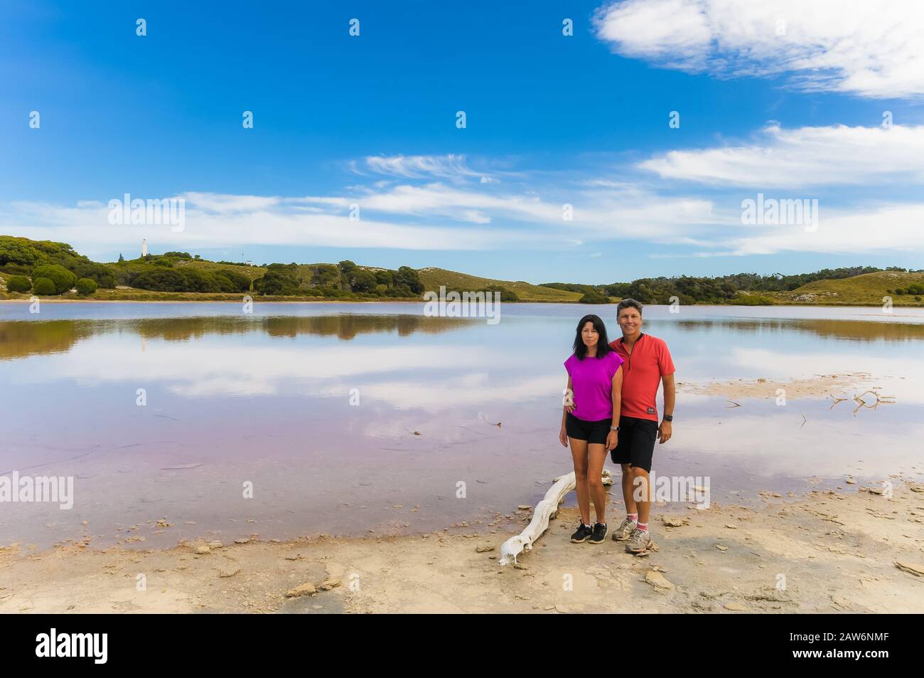 Una coppia in bicicletta intorno all'Isola di Rottnest in australia Occidentale fate una meritata pausa sulle rive del Lago Rosa. Foto Stock