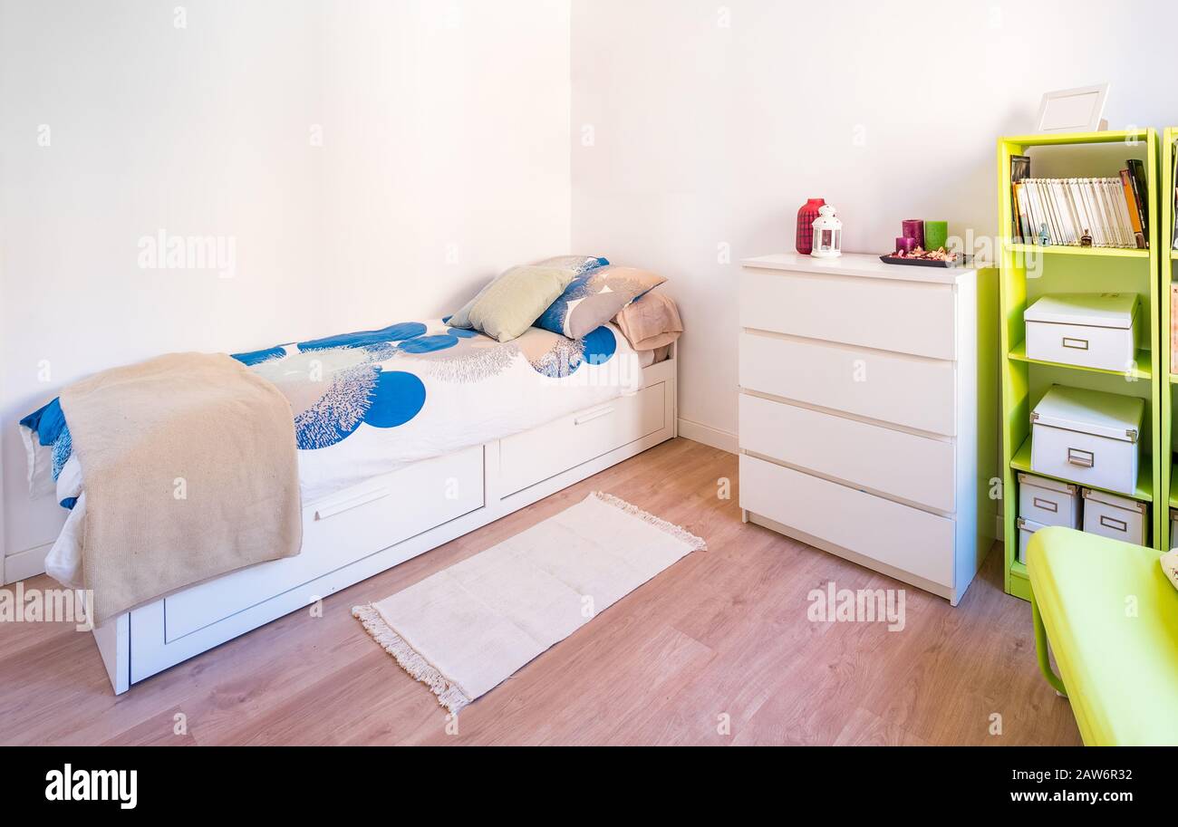 Camera da letto colorata e luminosa con letto, piumone, comodini, lampade e piante. Interni eleganti e minimalisti di colore bianco Foto Stock