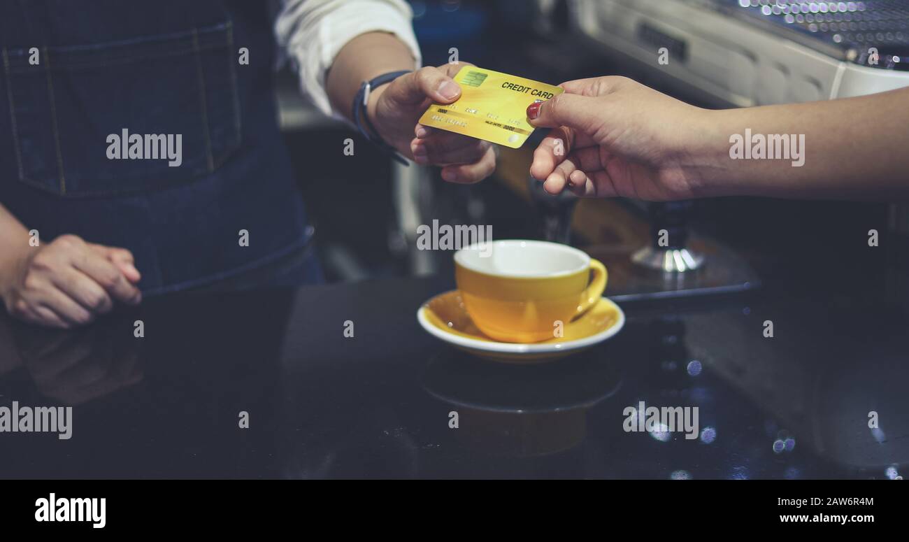 Il barista che serve il cliente e Woman paga il caffè con carta di credito nella caffetteria Foto Stock