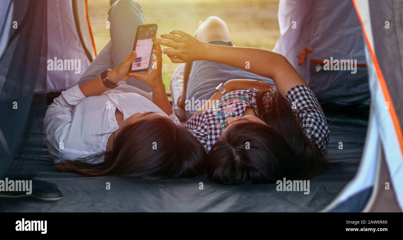 Un gruppo di amici asiatici che giocano Ukelele e trascorrere il tempo facendo un picnic in estate holidays.They sono felici e utilizzando smartphone per selfie ,Rel Foto Stock