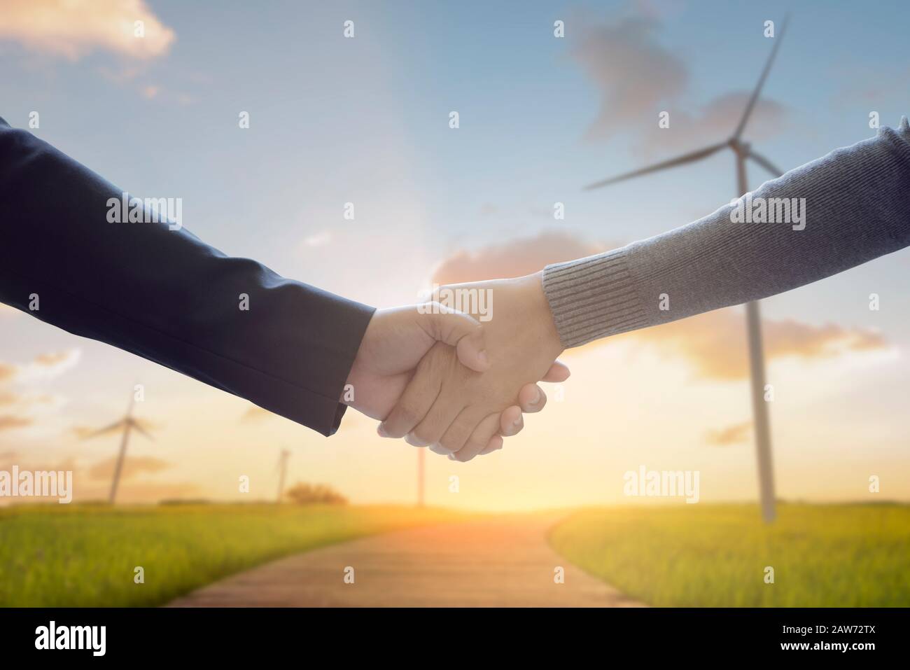 Handshake di businessperson che lavora con la tecnologia virtuale moderna con turbine eoliche in background come concetto di business rinnovabile e di cooperazione ambientale Foto Stock Handshake di businessperson che lavora con la tecnologia virtuale moderna con turbine eoliche in background come concetto di business rinnovabile e di cooperazione ambientale Foto Stock