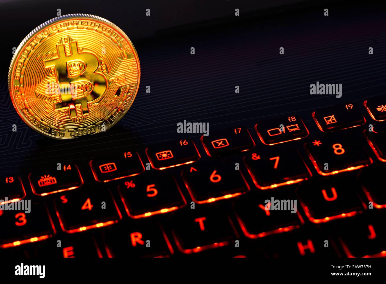 Bitcoin oro sul notebook con tastiera rossa. Una rappresentazione visiva delle criptovalute digitali. I Bitcoin sono completamente dematerializzati e decentrati Foto Stock