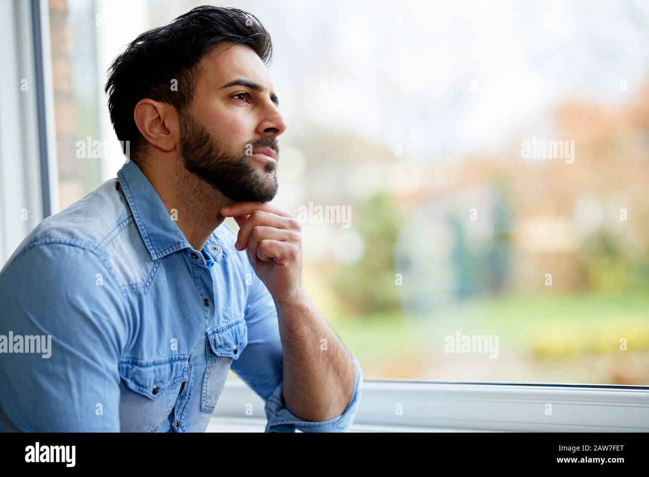 Uomo che guarda fuori della finestra Foto Stock