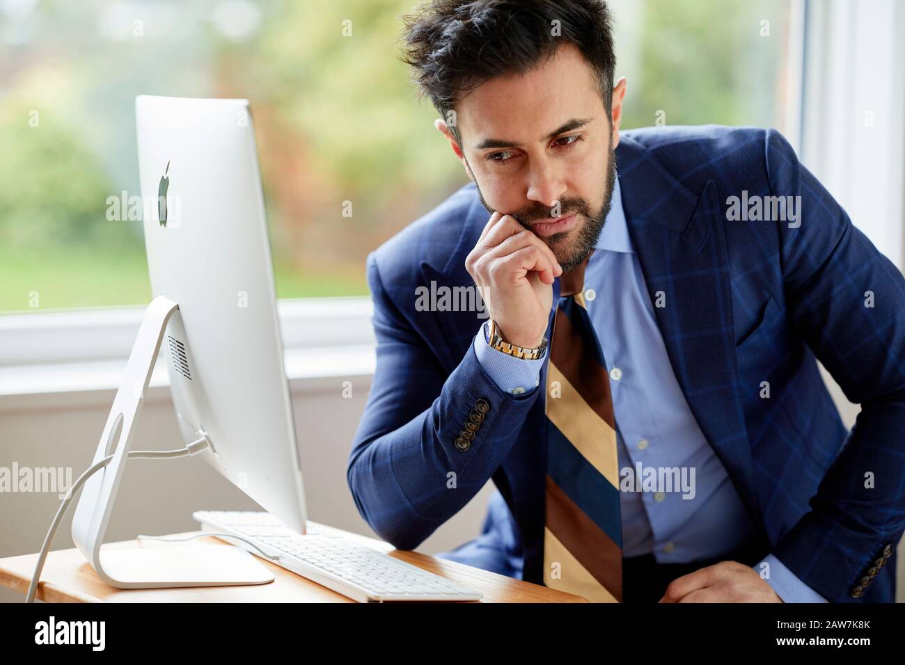 Uomo seduto al computer pensieroso Foto Stock