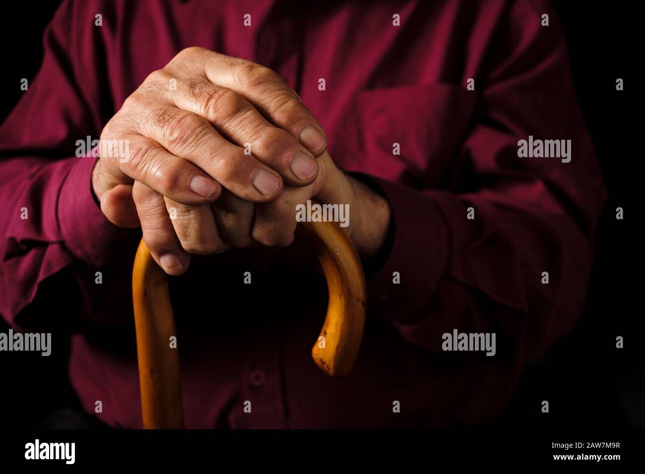 Uomo anziano che riposava le mani sul suo bastone da passeggio Foto Stock