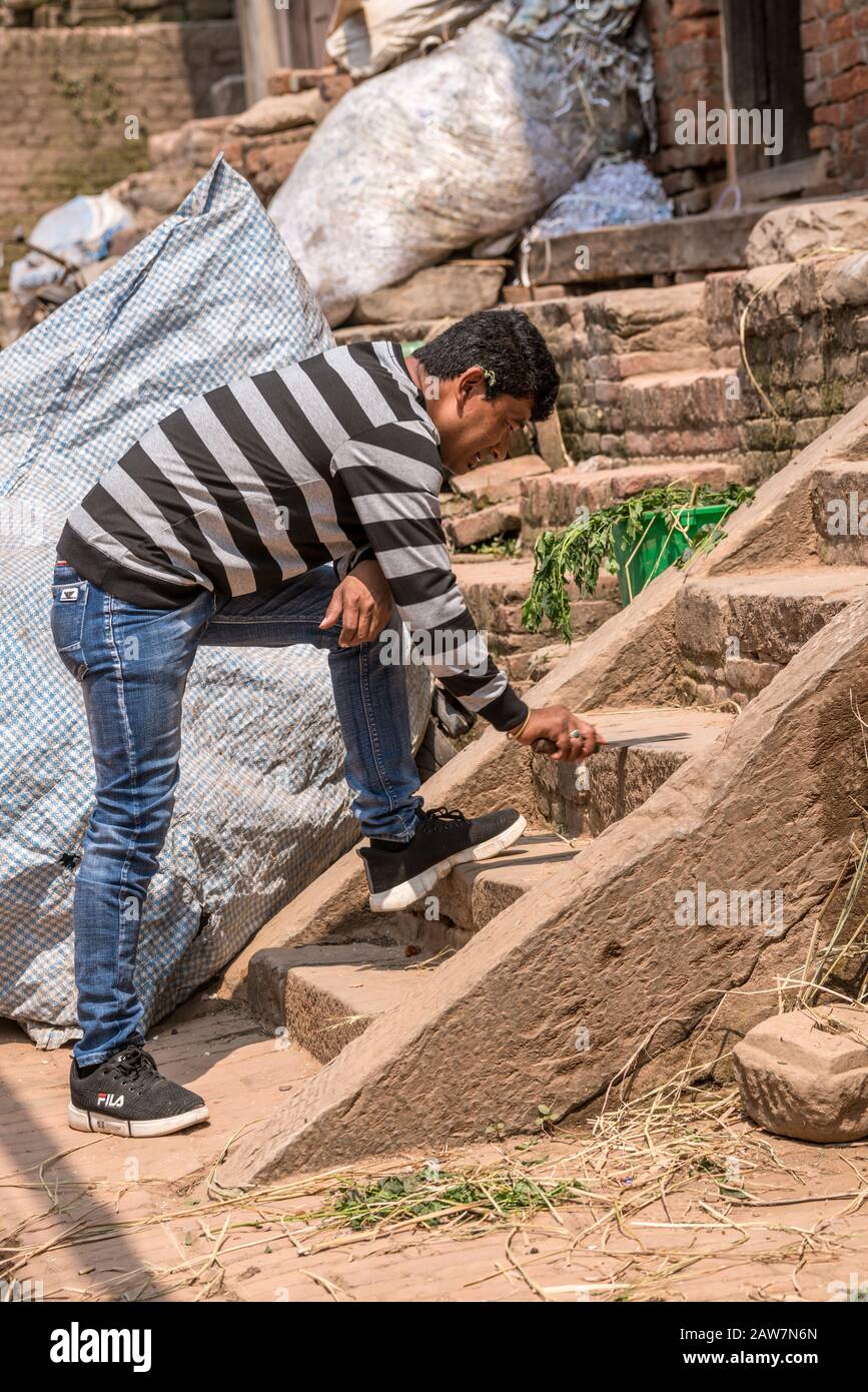 Un uomo affilando coltello su gradini di pietra a Bhaktapur durante il festival Bisket Jatra, valle di Kathmandu, Nepal Foto Stock