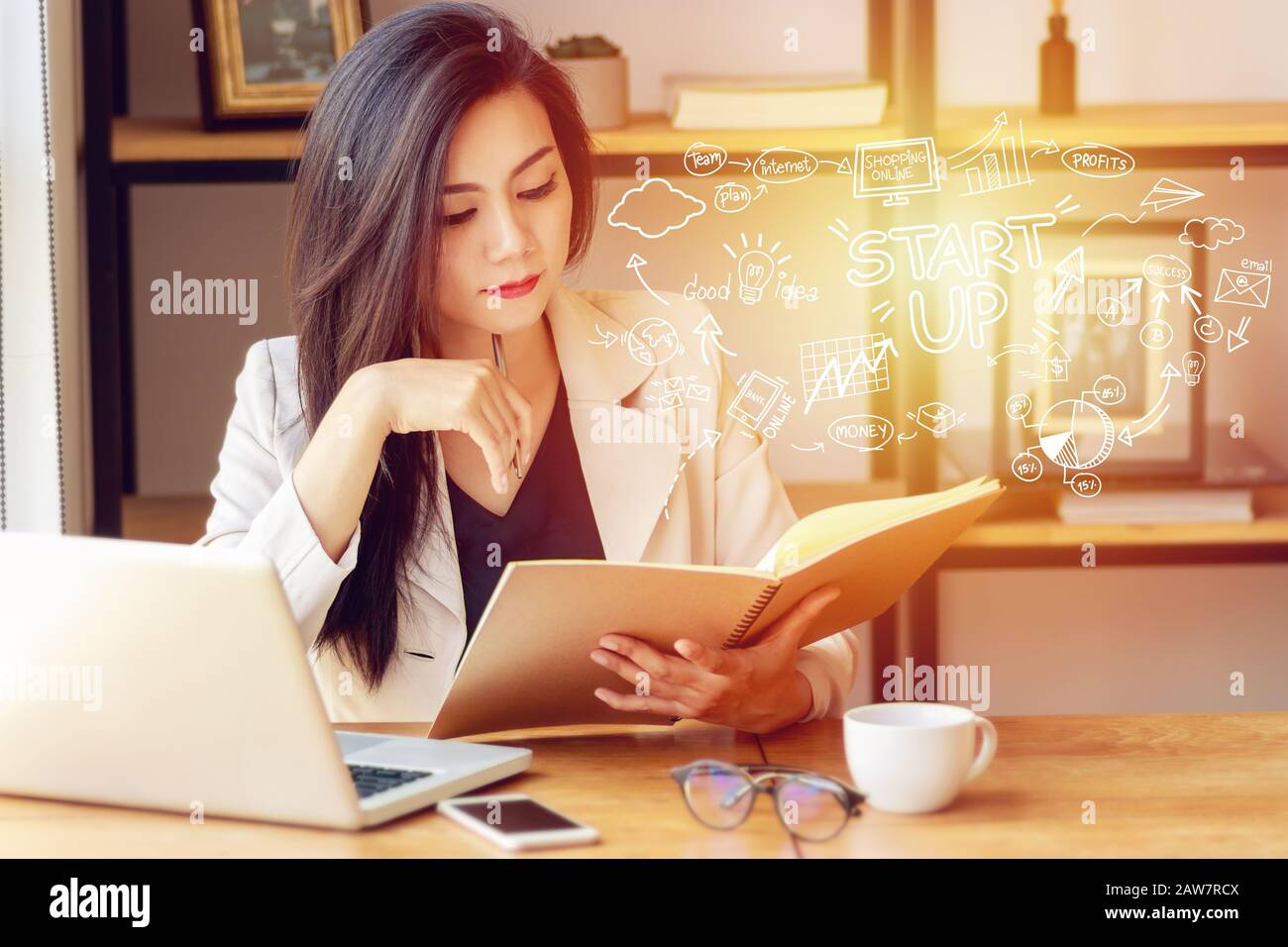 Ritratto di giovane donna asiatica seria seduto in ufficio con piano di business startup in primo piano Foto Stock