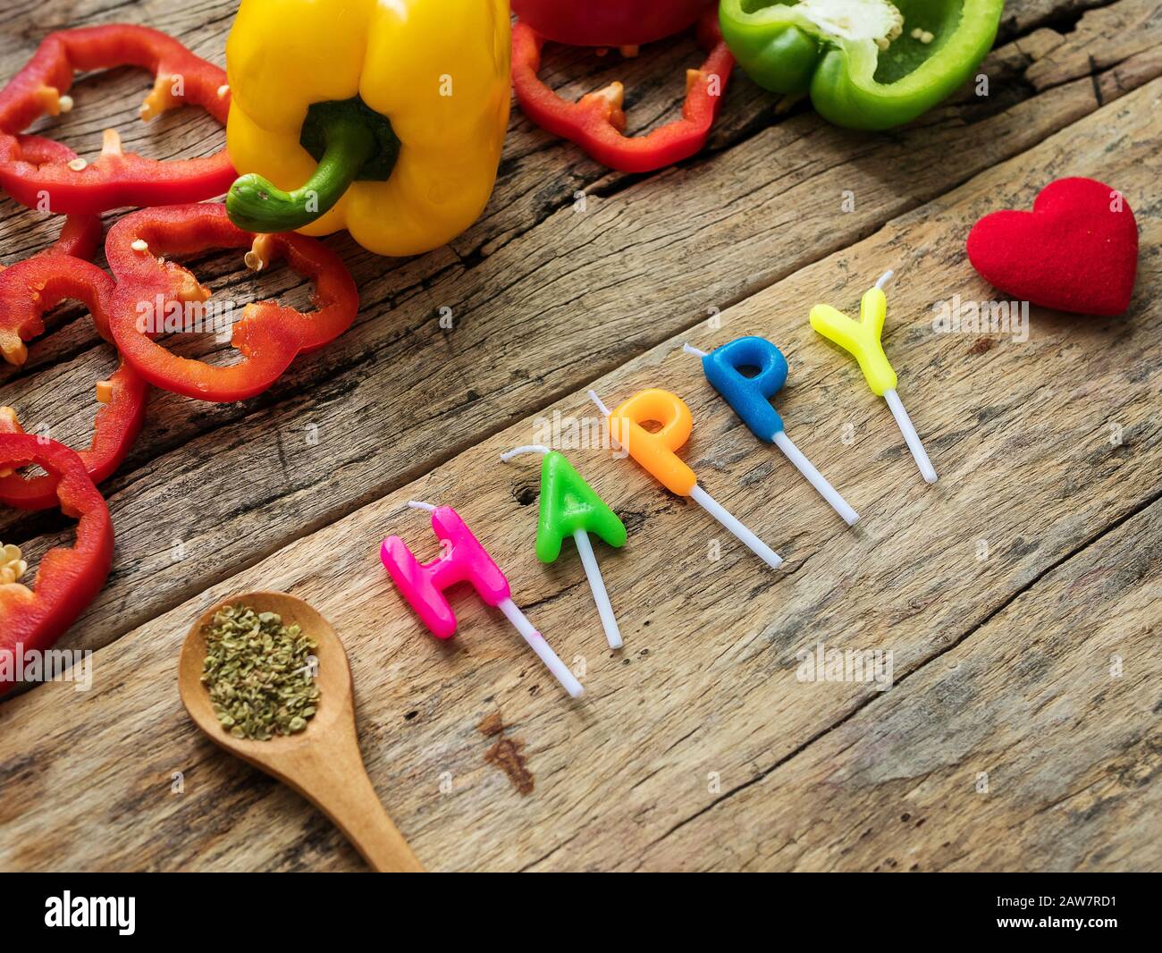 posate gli utensili da cucina con erbe, peperone colorato e la parola felice dalle candele su sfondo di legno. vista dall'alto con spazio per le copie. mangiate Foto Stock